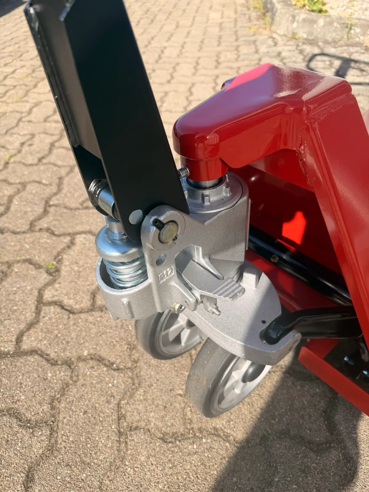 Detailansicht der Hydraulikpumpe und Lenkrollen des Handhubwagens